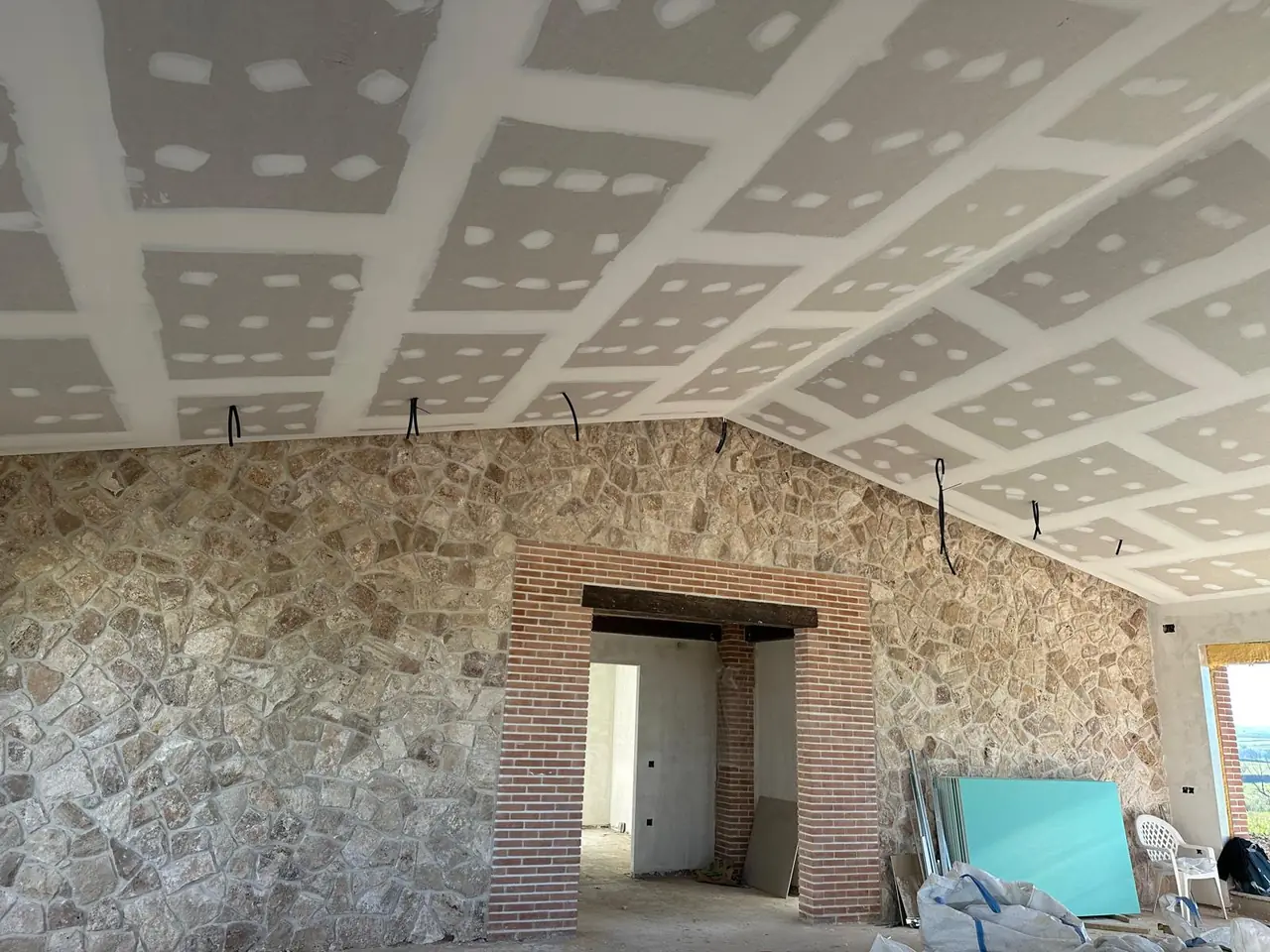 Techo inclinado sobre muro de piedra: falsos techos de pladur en vivienda. Obra de Docaplac